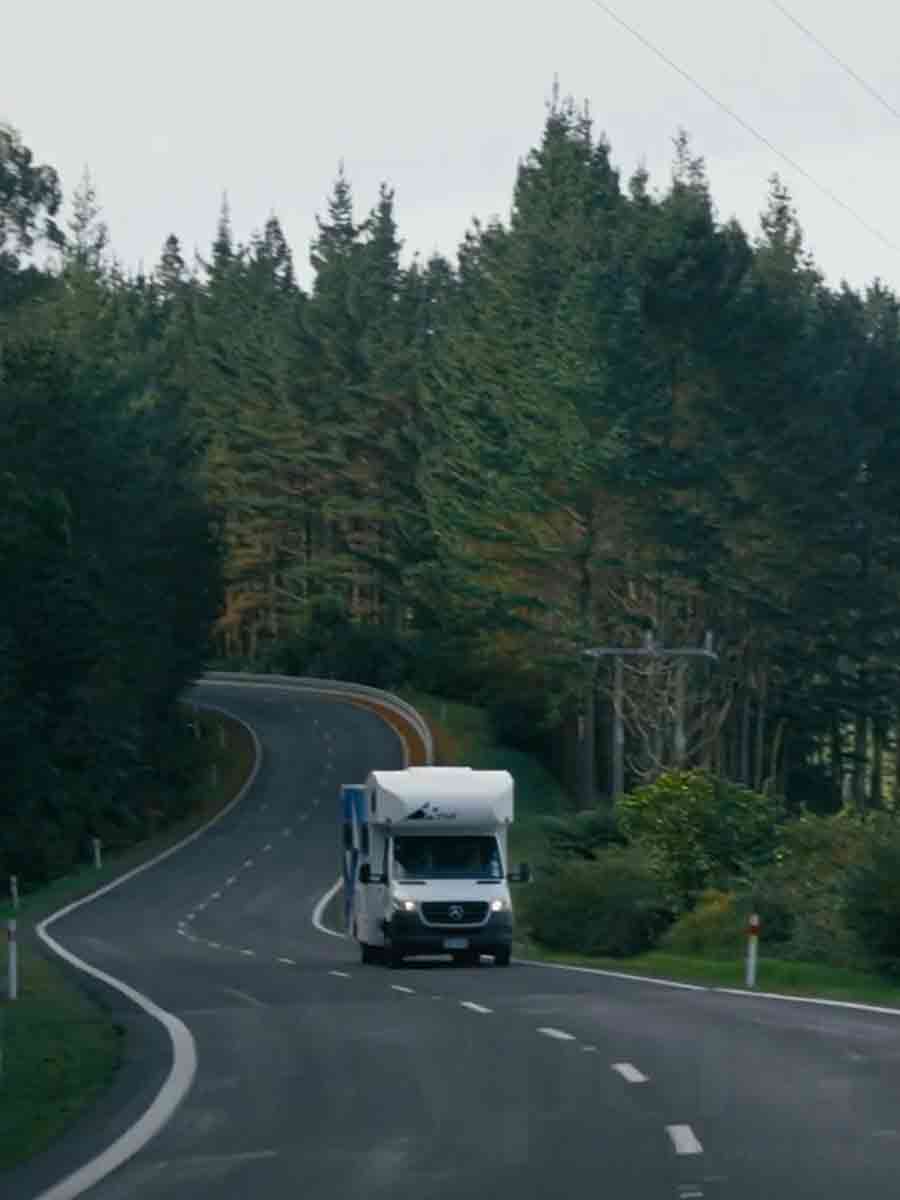 Star RV motorhome on the road winding through tall green trees
